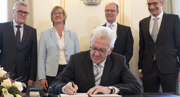 Ministerpräsident Winfried Kretschmann (vorne), Vorsitzender des Beamtenbundes Baden-Württemberg Volker Stich (l-r), Finanzministerin Edith Sitzmann, Matthias Grewe, Vorsitzender des Vereins der Richter und Staatsanwälte und Staatssekretär im Innenministerium Martin Jäger unterschreiben die Vereinbarung. Quelle: Michael Latz - dpa