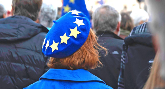 Eine Frau trägt einen blauen Hut mit gelben Sternen / Foto: Oliver Cole on Unsplash
