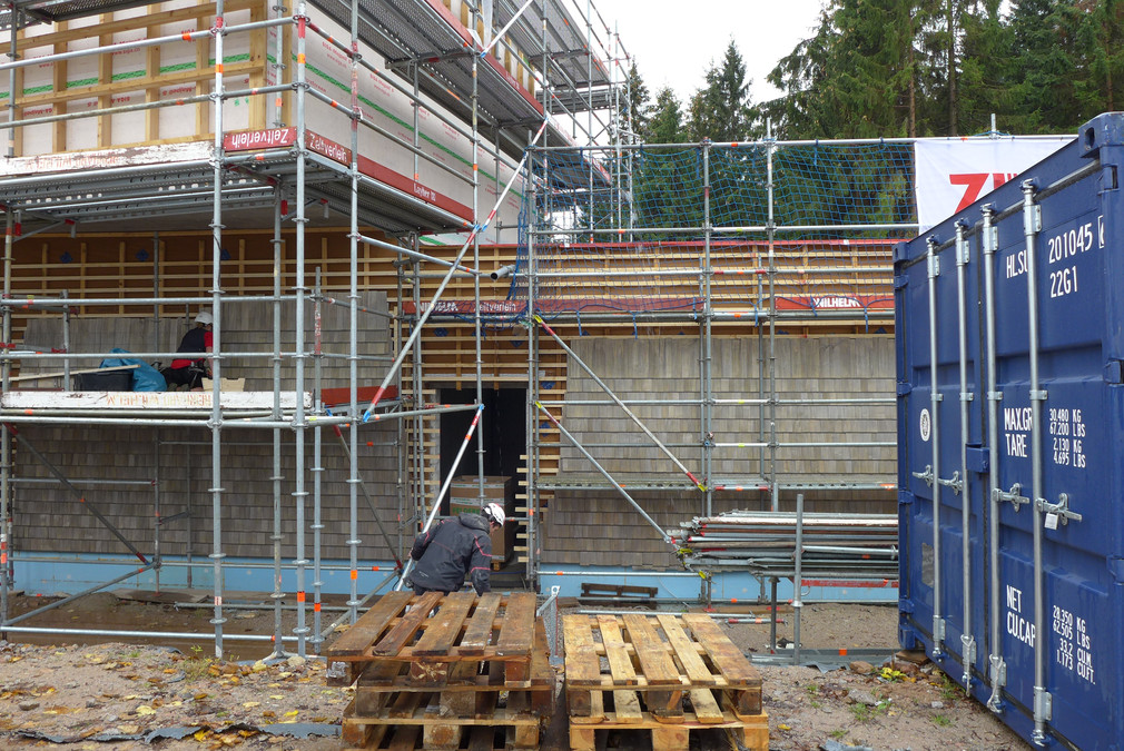 Bauarbeiter bringen die Schindeln an der Außenfassade des künftigen Nationalparkzentrums an (Foto: Vermögen und Bau Baden-Württemberg, Amt Pforzheim)