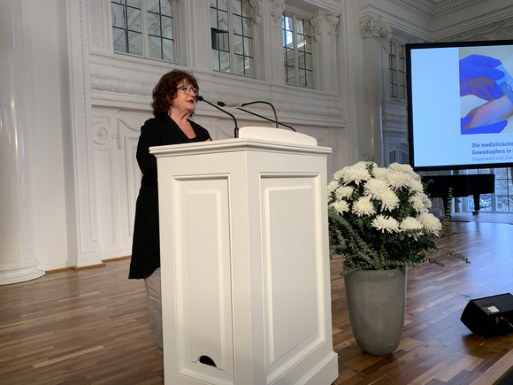 Grußwort Fachkongress „Medizinische Versorgung von Gewaltopfern in Baden-Württemberg“ Staatssekretärin Bärbl Mielich an Redepult vor Publikum
