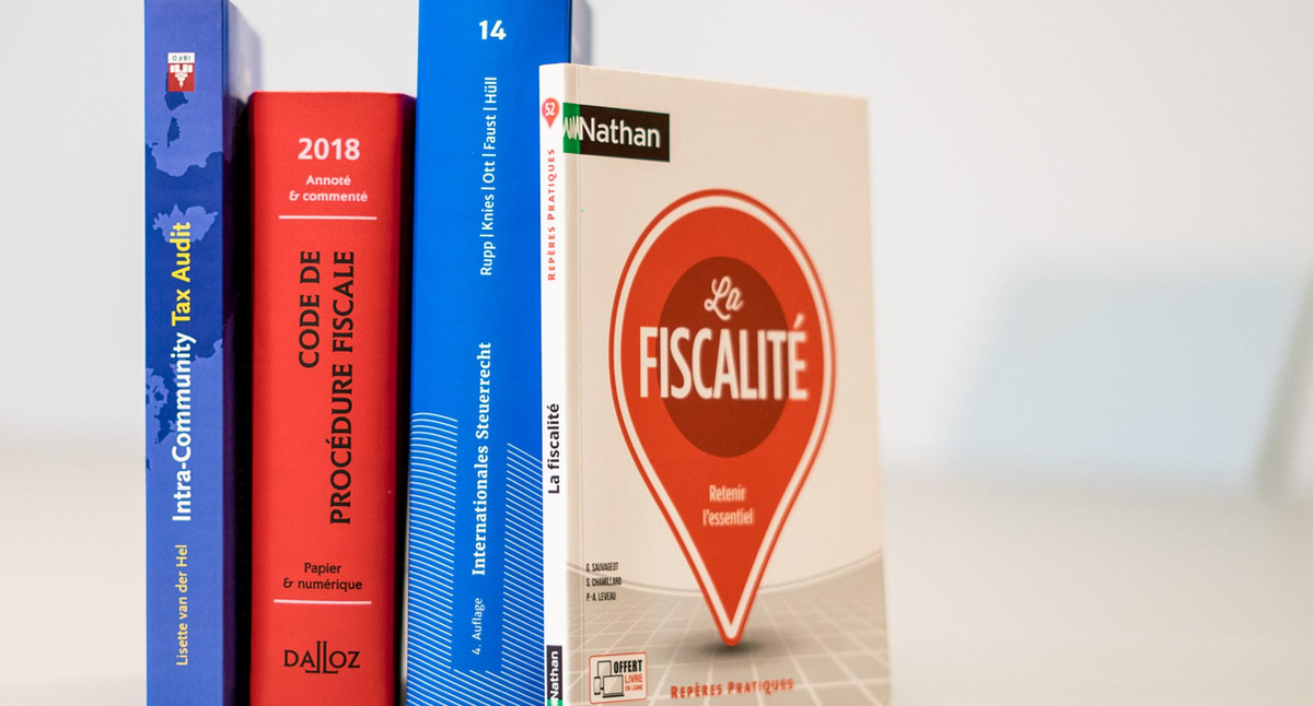 Vier Bücher über französisches und internationales Steuerrecht stehen auf einem Tisch.