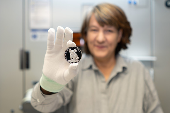 Staatssekretärin Gisela Splett hält die Vorderseite der frisch geprägten Medaille (Koala-Motiv) in die Kamera. 