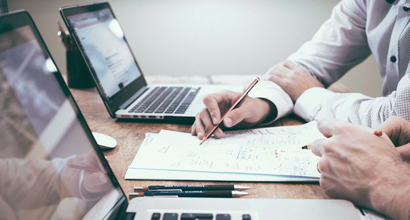 Mehrere Menschen mit Notizen und Laptops am Tisch / Foto: Scott Graham on unsplash