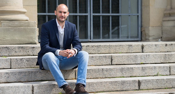 Finanzminister Dr. Danyal Bayaz sitzt auf Treppen vor dem Neuen Schloss in Stuttgart