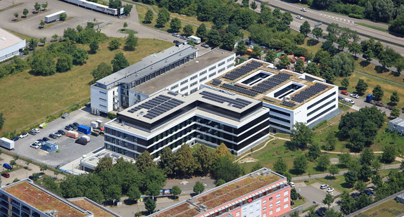 Luftaufnahme des neuen Büro- und Laborgebäudes der Landesanstalt für Umwelt Baden-Württemberg (LUBW) in Karlsruhe mit begrünten Dachflächen und Photovoltaikanlagen, umgeben von weiteren Bürogebäuden und Grünflächen.