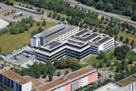 Hochbau Neues Büro- und Laborgebäude für die LUBW Luftaufnahme des neuen Büro- und Laborgebäudes der Landesanstalt für Umwelt Baden-Württemberg (LUBW) in Karlsruhe mit begrünten Dachflächen und Photovoltaikanlagen, umgeben von weiteren Bürogebäuden und Grünflächen.