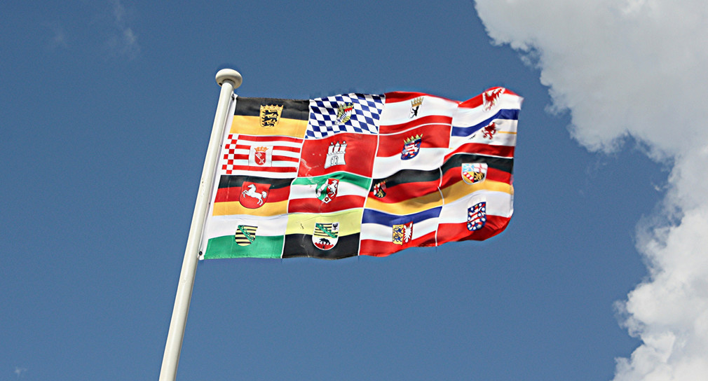 Bildmontage: eine wehende Flagge, zusammengestellt aus den Flaggen der 16 Bundesländer / Foto: ©Hero - stock.adobe.com